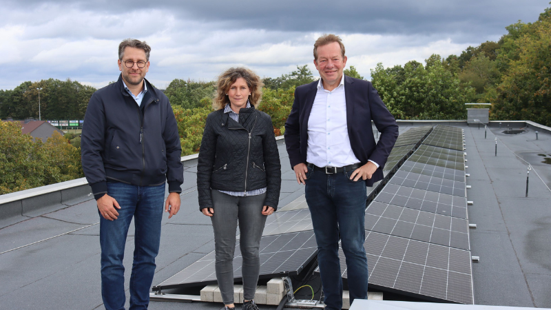 Sonne heizt Schule: Stadtbaurat Henrik Schumann, Schulleiterin Lidia Lipke und Bürgermeister Steffen Mues vor der neuen PV-Anlage auf dem Dach der Montessorischule Siegen. (Foto: Stadt Siegen)