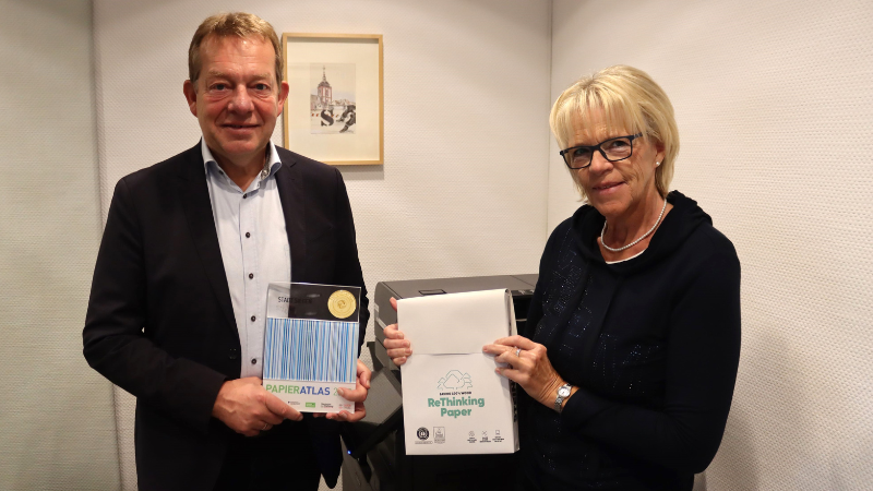 Bürgermeister Steffen Mues und Regina Stiller, Mitarbeiterin im Büro Bürgermeister, nahmen stellvertretend für die Stadt Siegen die Auszeichnung als „Mehrfachsieger“ für die konsequente Nutzung von Recyclingpapier entgegen. (Foto: Stadt Siegen)